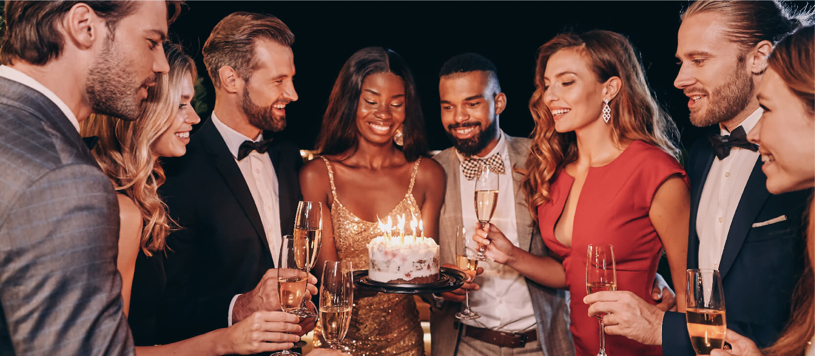Group of young friends celebrating and gathered around a birthday cake