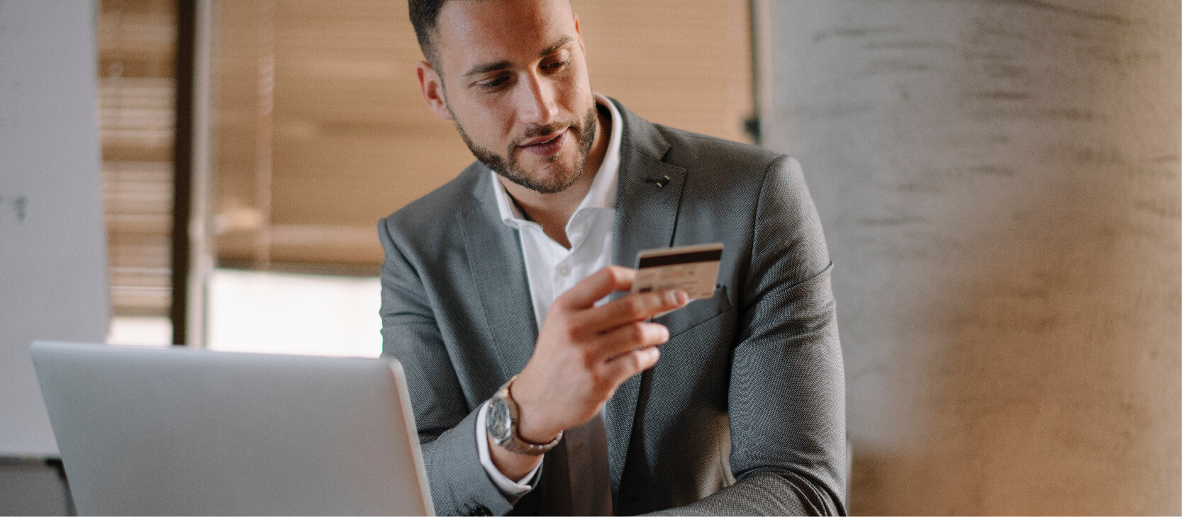 Younger professional shopping online and looking at his credit card